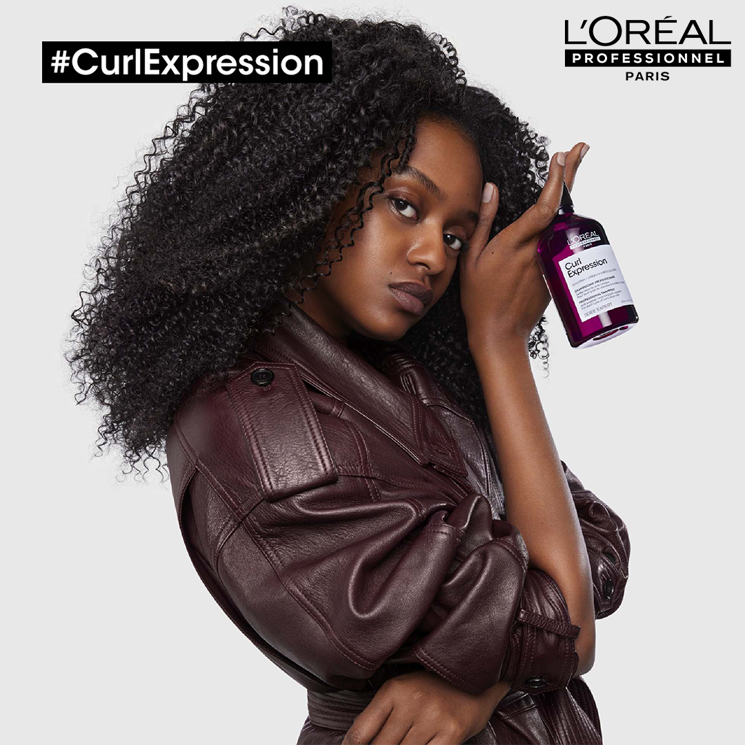 Kobieta narodowości afrykańskiej w ciemnej, skórzanej kurtce promująca markę L'Oreal Professionel Paris #CurlExpression.